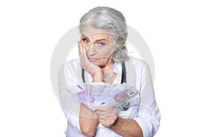 Mature female doctor with money posing on white background