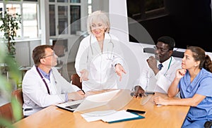 Mature female doctor speaks at meeting of colleagues and tells reports on condition of patients.