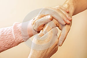 Mature female in elderly care facility gets help from hospital personnel nurse. Close up of aged wrinkled hands of senior woman. G