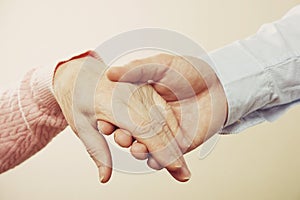 Mature female in elderly care facility gets help from hospital personnel nurse. Close up of aged wrinkled hands of senior woman. G