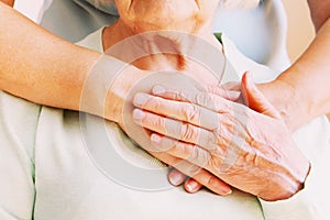 Mature female in elderly care facility gets help from hospital personnel nurse. Close up of aged wrinkled hands of senior woman. G