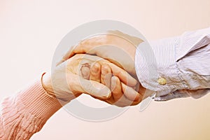 Mature female in elderly care facility gets help from hospital personnel nurse. Close up of aged wrinkled hands of senior woman. G