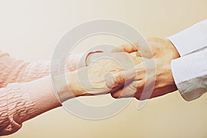 Mature female in elderly care facility gets help from hospital personnel nurse. Close up of aged wrinkled hands of senior woman. G