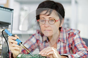 Mature female electronic engineer soldering computer