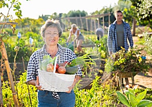 Mature female gardener posing with harvested vegetables