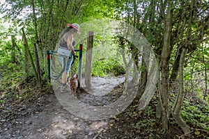 Mature female hiker with her brown dachshund walking and crossing metal revolving gate