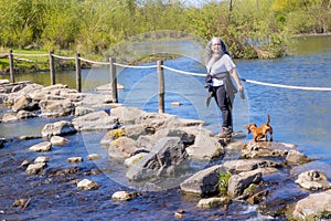 Mature female hiker with her dachshund standing on the stepping stones of Brug Molenplas