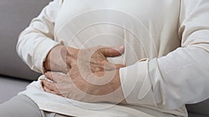 Mature female holding hands on tummy, abdominal pain, gastritis health problem