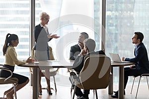 Mature female manager speaking to executive team at group meeting