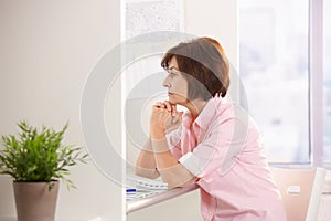 Mature female office worker thinking at desk