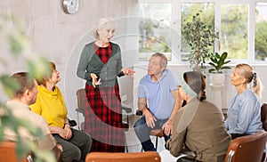 Mature female psychologist conducting a group session with mature clients