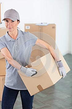 mature female removals worker carrying cardboard box photo