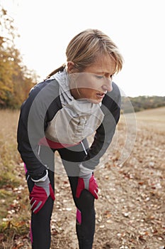 Mature Female Runner Pausing For Breath During Exercise In Woods photo