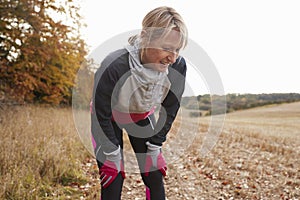 Mature Female Runner Pausing For Breath During Exercise In Woods photo