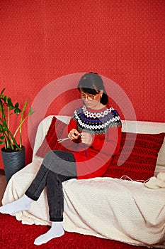 Mature female sitting in comfortable sofa and knitting