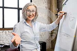 Mature female teacher writing on a whiteboard