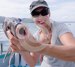 Mature female tourist smiling holding Porae fish caught on fishing charter boat in Far North District, Northland, New Zealand, NZ photo