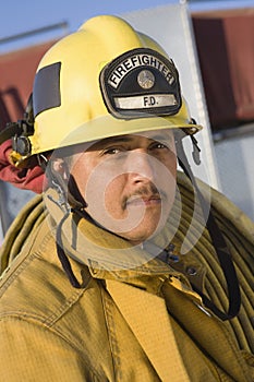 Mature Fire Fighter Carrying Fire Hose On Shoulder