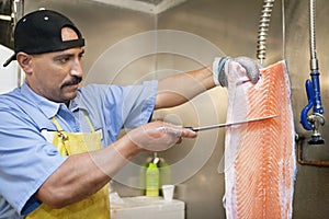 Mature fishmonger slicing salmon fish