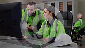 Mature foreman in uniform help young asian woman engineer working on computer