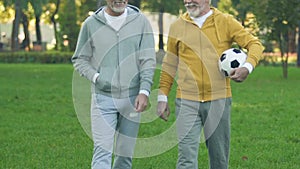 Mature friends with ball going to play football, sport team of pensioners, hobby