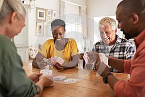 Mature friends playing cards at home