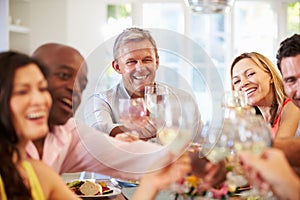 Mature Friends Sitting Around Table At Dinner Party