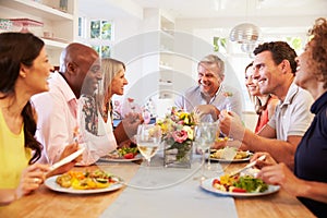 Mature Friends Sitting Around Table At Dinner Party photo