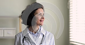 Mature general practitioner woman smile looks out window