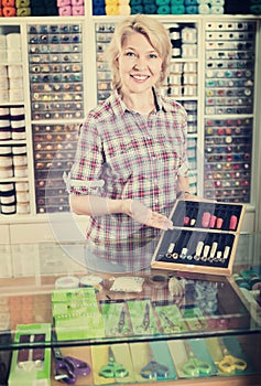 Mature glad woman seller holding box with thimbles