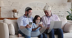 Mature grandfather and father watching kid browsing Internet on smartphone