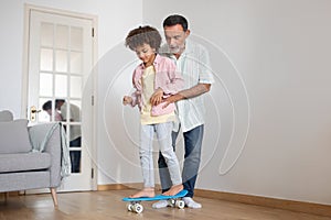 Mature Grandpa Teaching His Grandchild To Ride Skateboard At Home