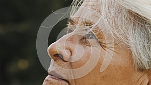 Mature gray haired woman enjoyng autumn breeze in park. Close up