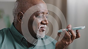 Mature grey-haired 60s biracial man with beard african american senior old male at home hold smartphone speak to phone