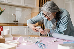 Mature grey woman taking photo of jewelery on her cellphone