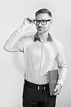mature grizzle man in eyeglasses hold pc on grey background