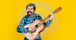 Mature guitarist playing the guitar on yellow background, vocal