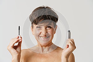 Mature half-naked woman smiling while showing mascara