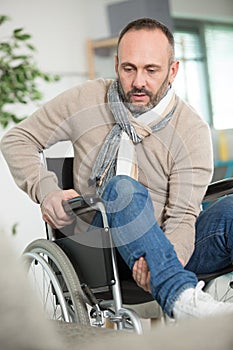 mature handicapped man lifting leg into position on wheelchair