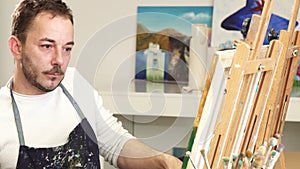 Mature handsome male artist smiling talking on the phone while painting