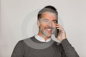 Mature handsome man smiling and talking on the phone. He is looking away. Isolated on white. Good news.