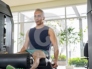 Mature handsome Persian man doing leg extension exercise at the gym