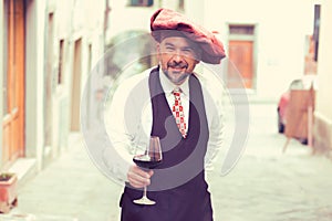 Portrait of a mature happy man with glass of red wine outdoors in old italian village