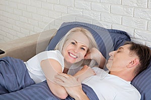 Mature heterosexual beautiful couple lying on bed in bedroom