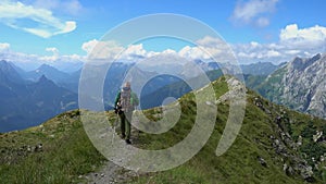 Mature hiker walking on trail on top mountains