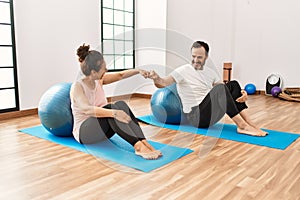 Mature hispanic couple doing excersice and stretching at yoga room