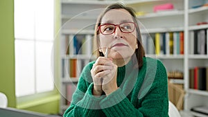 Mature hispanic woman with grey hair thinking at library