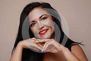Mature Hispanic woman with red lips, posing and smiling over white background.