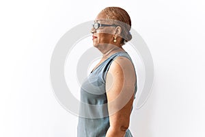Mature hispanic woman wearing glasses standing over isolated background looking to side, relax profile pose with natural face and