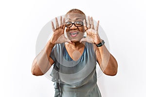Mature hispanic woman wearing glasses standing over isolated background smiling cheerful playing peek a boo with hands showing